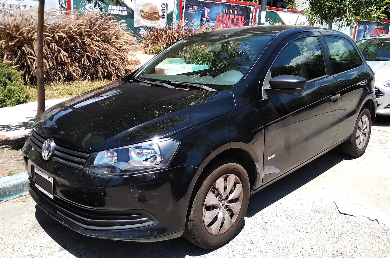 Volkswagen Gol Trend negro de tres puertas, visto desde adelante y de costado, con la insignia Trend en la puerta y tapas de rueda.